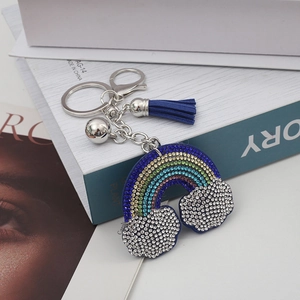 Dettaglio del portachiavi arcobaleno con strass, nappa blu e ganci in metallo argentato
