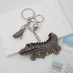 Detailed view of rhinestone crocodile keychain with grey suede tassel and silver clasp