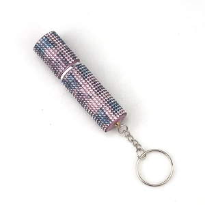 Detailed macro view of portable pink and blue rhinestone-encrusted 10ml perfume atomizer