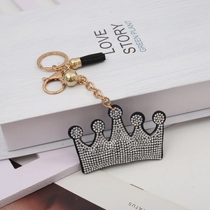Detailed macro view of a crystal-encrusted crown keychain with black tassel and golden hardware