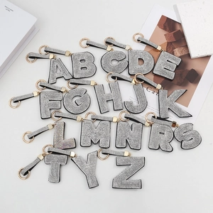 Vue à plat de porte-clés lettres en strass de luxe avec rubans noirs et métal doré