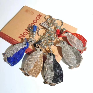 Detail view of five crystal penguin keychains with colorful tassels on a notebook