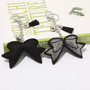Dettaglio portachiavi a fiocco con strass bianchi, materiale scamosciato e nappina nera
