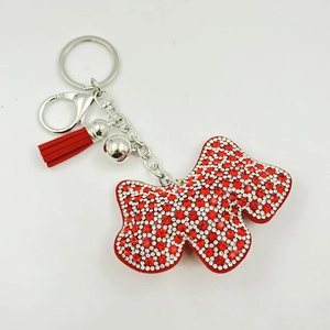 Dettaglio di portachiavi a farfalla con strass rossi e bianchi, campanello e nappa in pelle