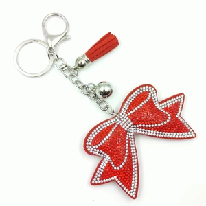 Dettaglio portachiavi a fiocco rosso con strass, nappa in pelle e campanellino argento