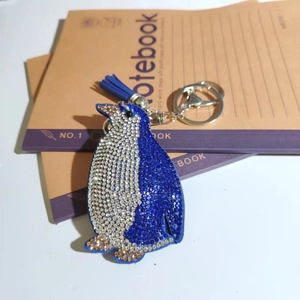 Detail of blue rhinestone penguin keychain with matching tassel on a notebook