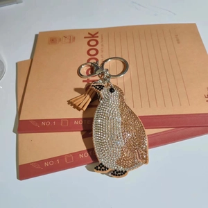 Detailed view of rhinestone penguin keychain with brown tassel and silver metal clasp