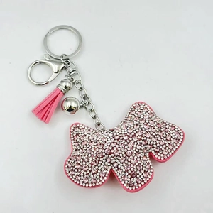 Dettaglio portachiavi a forma di cane con strass rosa, nappa in camoscio e sfera