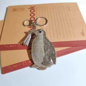 Detail of penguin keychain with silver rhinestones, gold accents, and grey tassel