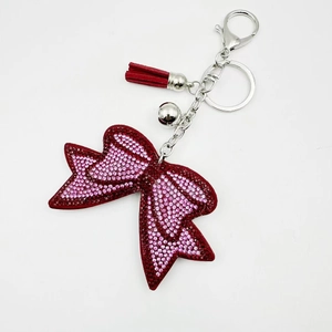 Dettaglio portachiavi a fiocco con strass rosa, nappa in pelle rossa e campanelli d'argento