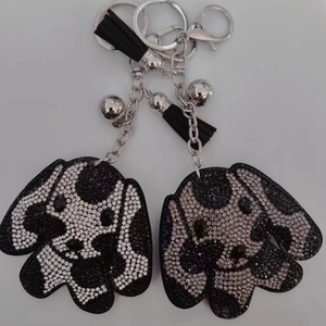 Détail du porte-clés chien en cristaux avec pompon en cuir noir et clochette argentée