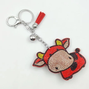 Détail du porte-clés vache de dessin animé avec strass rouges et gland rouge