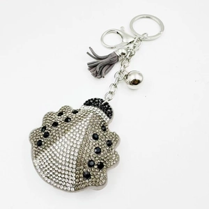 Détail d'un porte-clés coccinelle serti de strass avec pompon gris et fermoir mousqueton argent