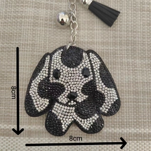 Détail d'un porte-clés chien en strass de 8cm avec pompon en cuir noir et clochette argent