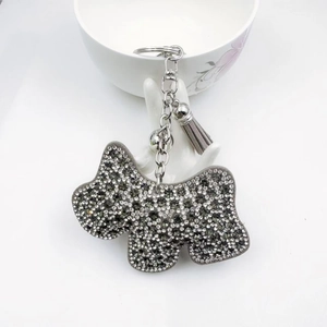 Dettaglio portachiavi a forma di cane con strass grigi, campanellino e nappa in pelle