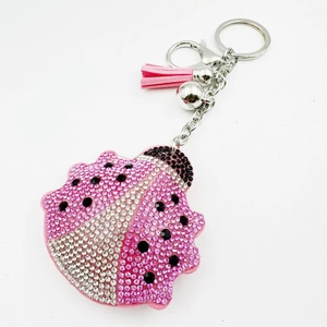 Détail d'un porte-clés coccinelle rose orné de strass brillants et d'un pompon soyeux