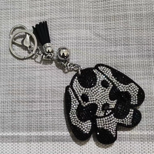 Détail d'un porte-clés chiot en strass avec pompon noir et anneau en métal argenté