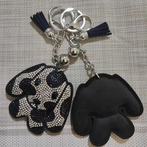 Détail du porte-clés chien en strass avec pompons noirs et fermoir en métal argenté