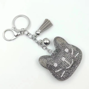 Detail of gray rhinestone bear keychain with plush tassel and silver metal hardware