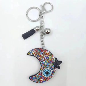Close-up of colorful rhinestone crescent moon keychain with black tassel and silver bell