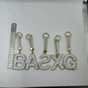 Assorted gold alloy alphabet and number keychains with shimmering white rhinestones