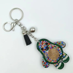 Dettaglio macro del portachiavi avocado in strass con nappa in pelle e anello argento