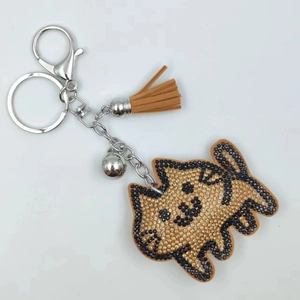 Detailed view of cat keychain with gold rhinestones, brown suede tassel and silver bell