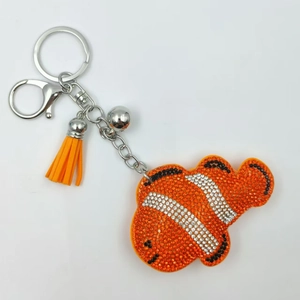 Porte-clés poisson-clown en strass avec frange orange et clochette sur fond blanc