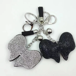 Close-up of bow-tie keychains with rhinestones and black leather tassels in two colors