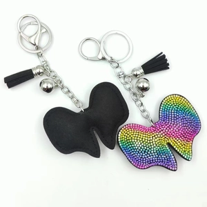 Detail of bow-tie keychains featuring rhinestone embellishments and black leather tassels