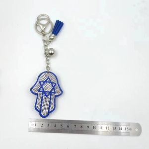 Detailed view of Hamsa Hand keychain with blue tassels and rhinestones measured by a ruler