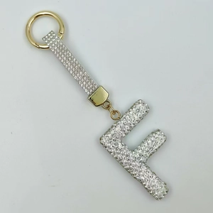 Detailed view of rhinestone letter F keychain with golden hardware and white strap