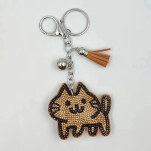 Close-up of rhinestone cat keychain with leather tassel, metal bell, and lobster clasp