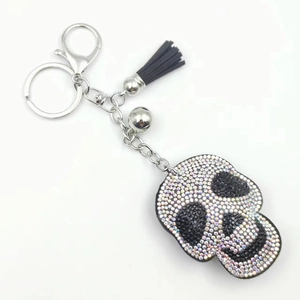Close-up of skull keychain with colorful rhinestones, black leather tassel, and silver bell