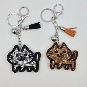 Close-up of sparkling rhinestone cat keychain with leather tassel and silver bell detail