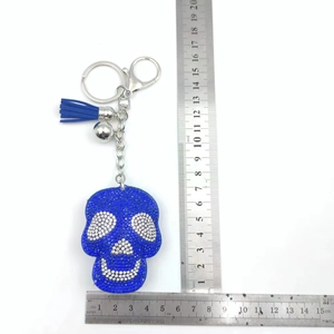 Detailed scale measurement of a blue rhinestone skull keychain with tassel and bell
