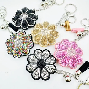 Détail de porte-clés fleurs étincelants avec strass colorés et pompons en cuir élégants