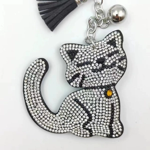 Detail of cartoon cat keychain with black and white rhinestones, silver bell and tassel