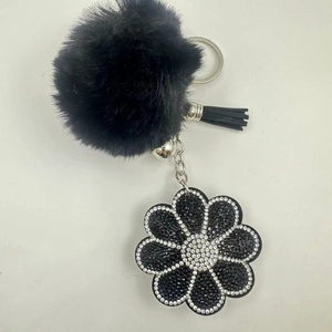 Detailed macro view of black faux fur ball keychain with rhinestone flower and tassel