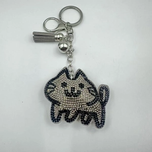 Close-up of sparkling rhinestone cat keychain with silver metal lobster clasp and grey tassel
