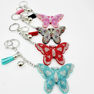 Détail de quatre porte-clés papillon en cristal avec strass et glands en cuir coloré