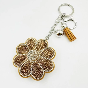 Détail du porte-clés tournesol avec cristaux brillants et pompon en daim marron