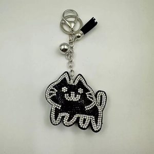 Detail of a black rhinestone cat keychain featuring a tassel, silver bell and lobster clasp