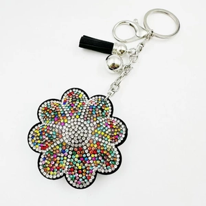 Détails du porte-clés tournesol avec strass colorés et un gland noir sur fond blanc neutre