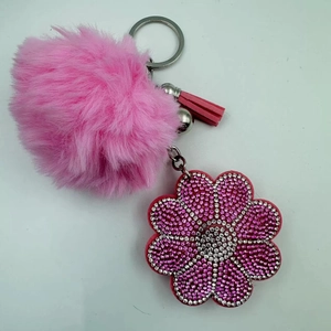 Detailed close-up of pink pom-pom keychain with rhinestone flower charm and leather tassel