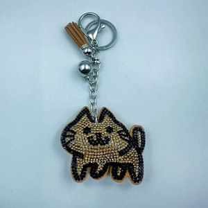 Detailed view of cat keychain with gold and black rhinestones and brown tassel detail