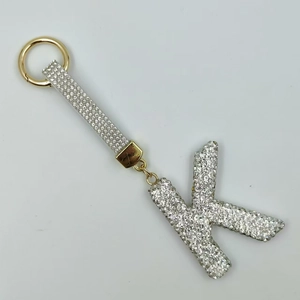 Close-up of sparkling rhinestone-encrusted letter K keychain with golden hardware and strap