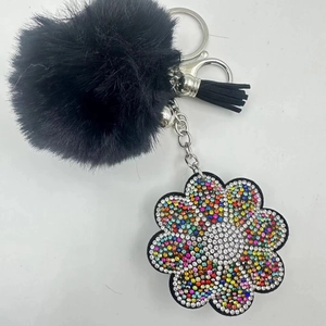Detail view of black faux fur pompom keychain with colorful rhinestone floral charm