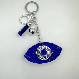 Detailed close-up of blue rhinestone Evil Eye pendant with leather tassel and silver bell