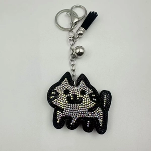Detail of a black cat keychain with rainbow rhinestones, silver bell, and tassel charm